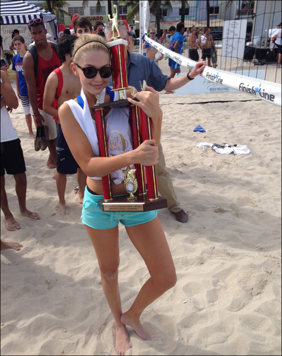 Gigi, who kept her junior Olympic volleyball experience under wraps during the models vs. celebrity chefs volleyball tournament, clings to her team's trophy. The unwieldy prize went home with Gigi to NYC, warranting its own seat on the charter flight.